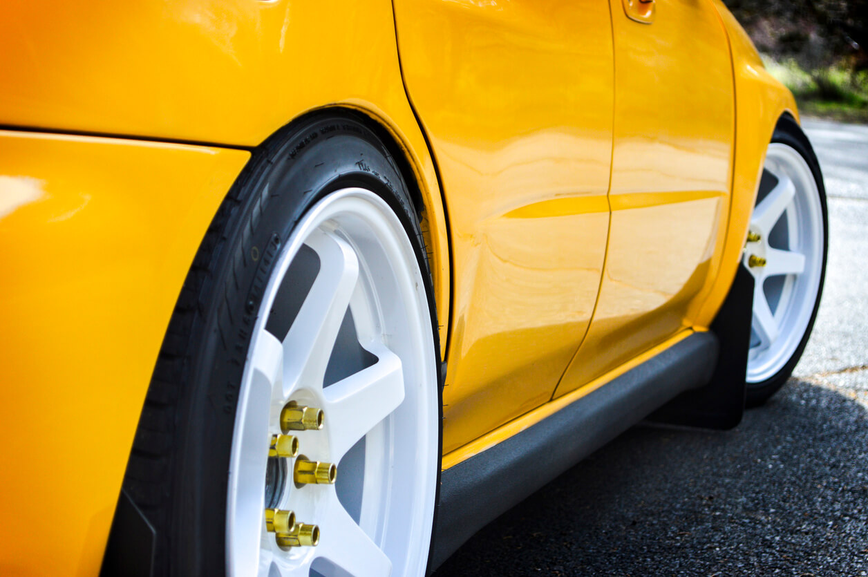 Yellow Subaru with white wheels.