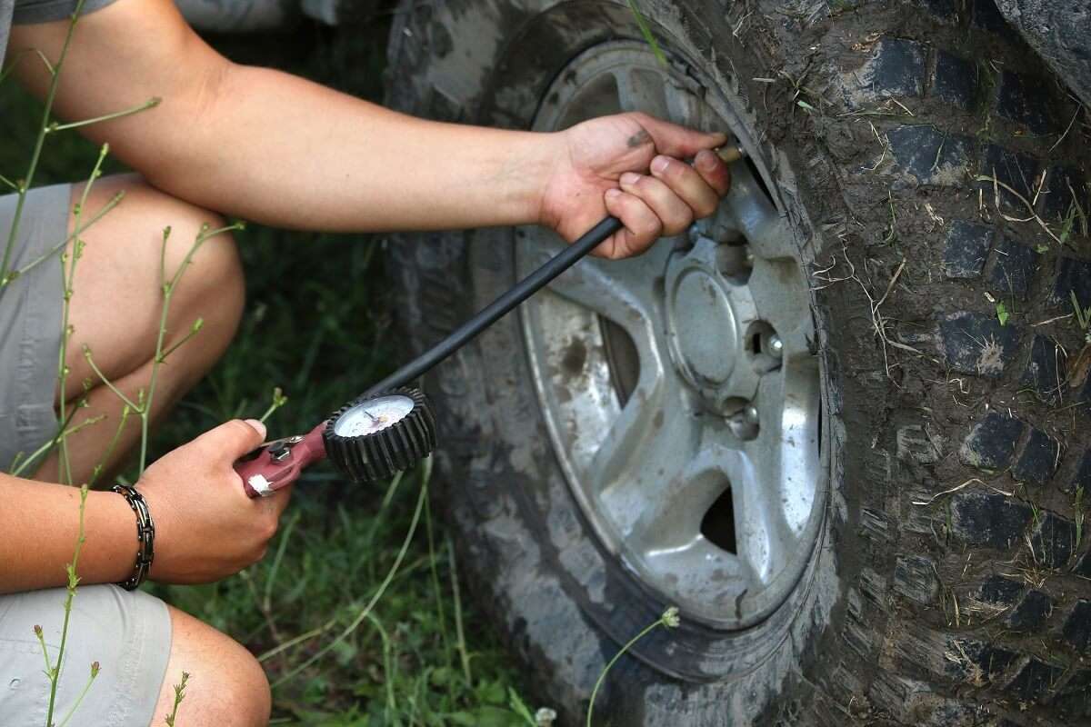 Person checking their tyre pressure with a gauge.