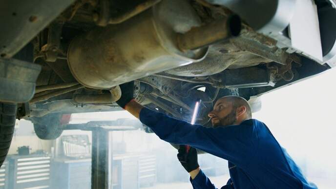 A man inspects a vehicle and performs car maintenance