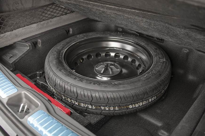A full sized spare tyre sits in the spare space in the boot of a car.